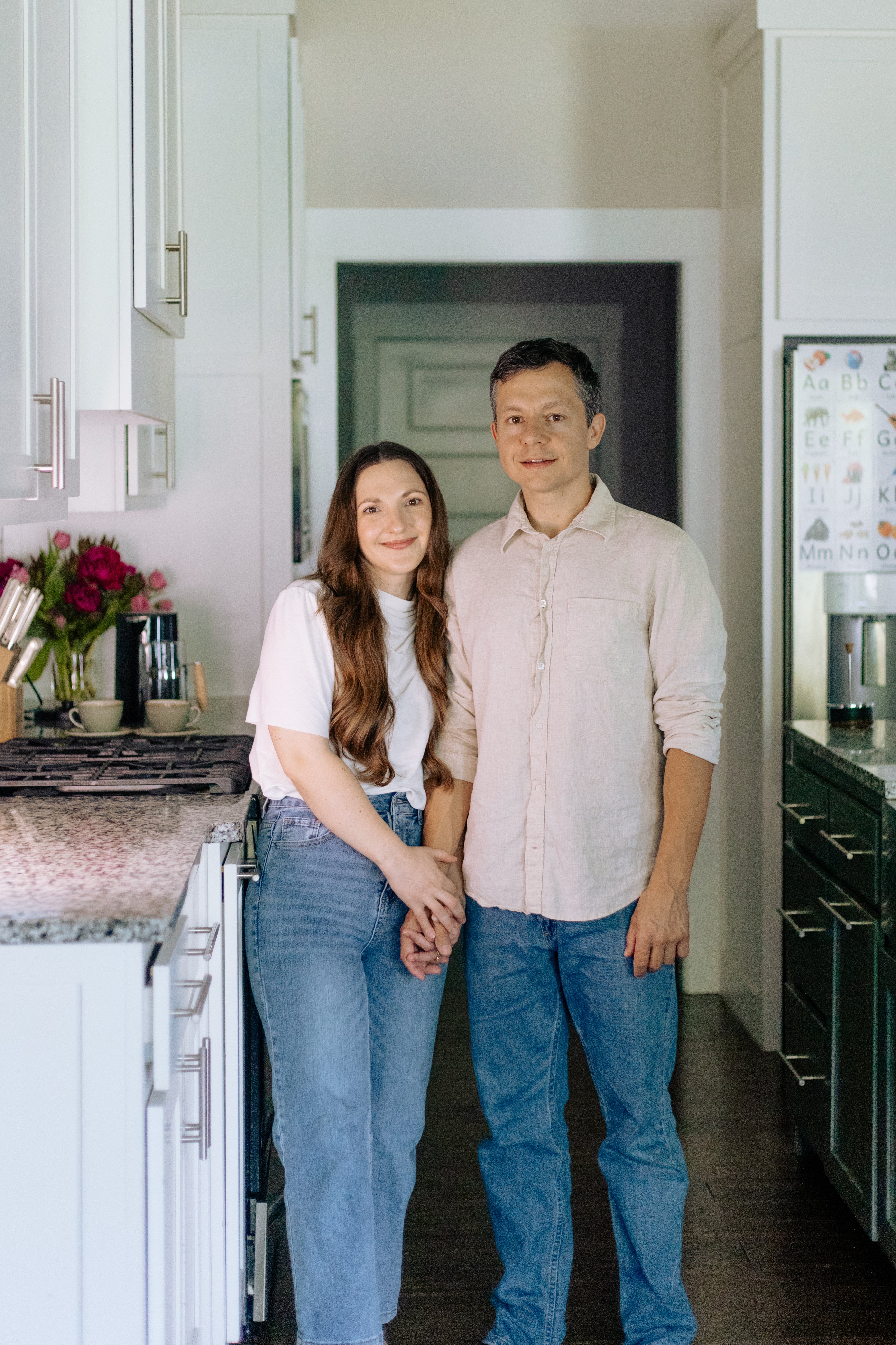 Two people standing in a kitchen holding hands