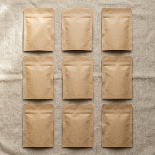 Nine blank brown kraft paper stand-up pouches arranged in a 3x3 grid on a textured beige linen fabric background.
