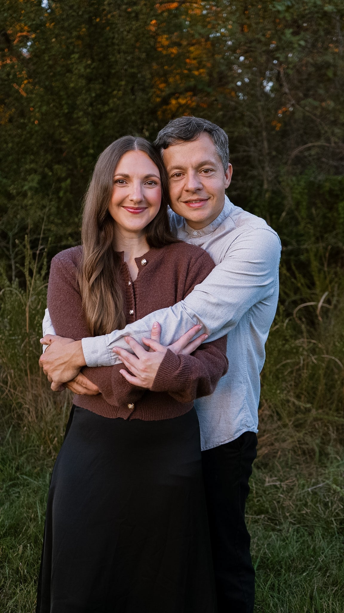 Couple embracing outdoors with greenery in the background