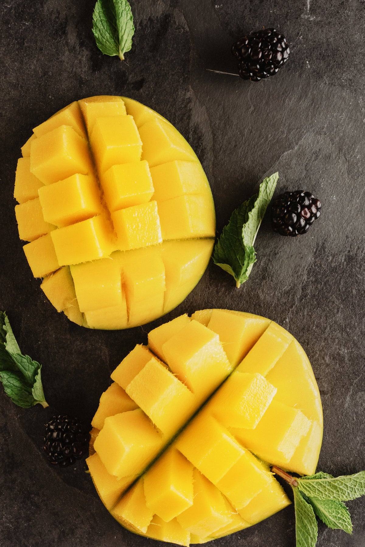 Mango sliced with mint on black background.