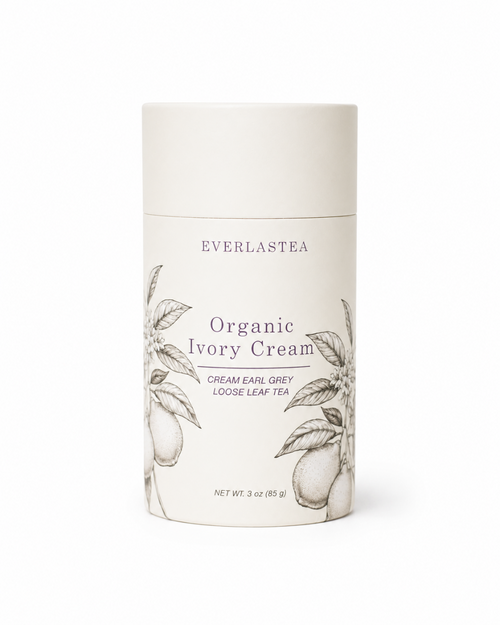A cylindrical white container of Everlastea Organic Ivory Cream, featuring elegant black botanical illustrations of tea leaves and pods on the label.
