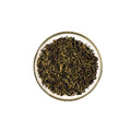 Dry organic jasmine gold dragon green tea leaves in a glass bowl on a white background